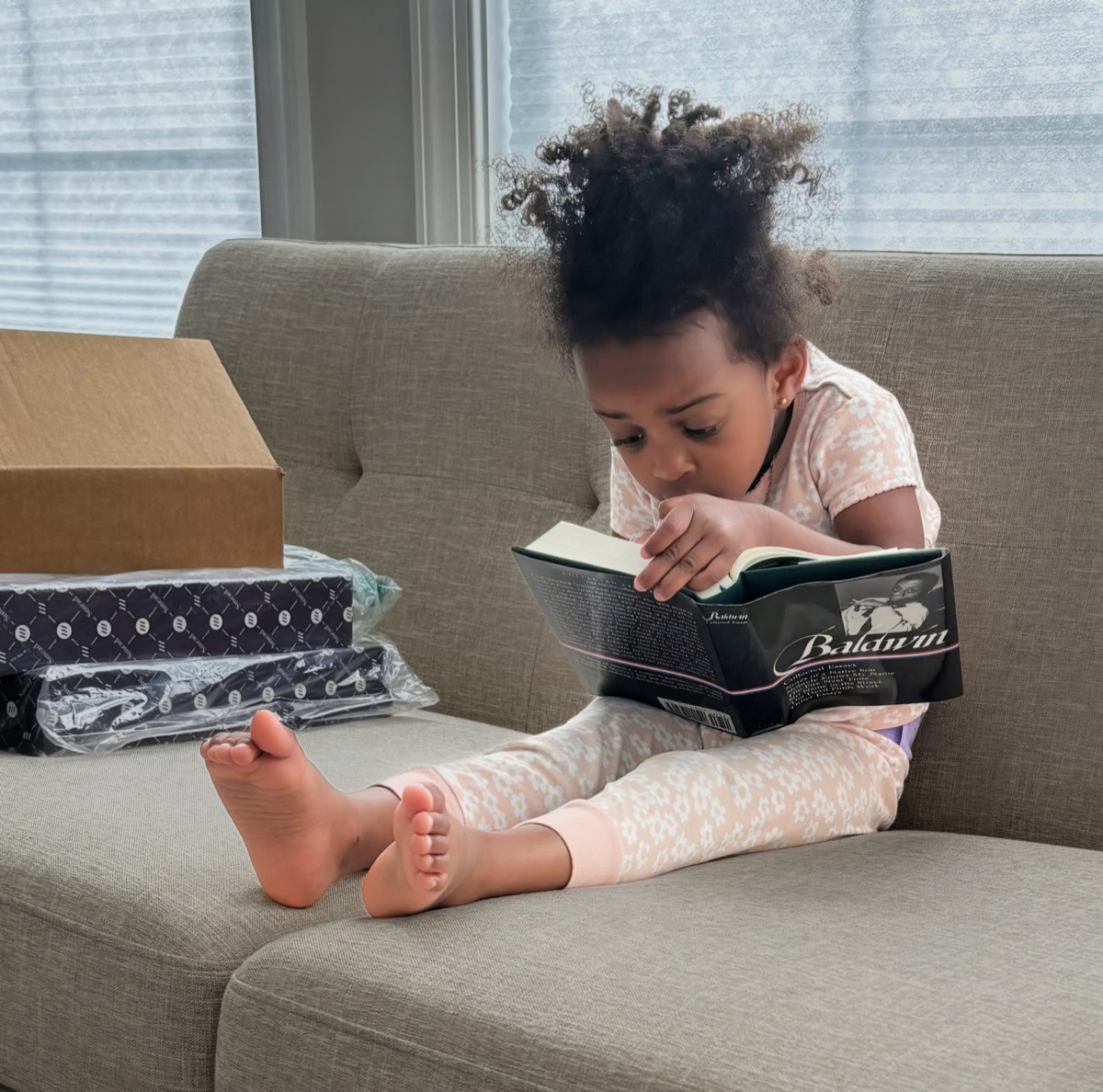 Yohanna curled up on the couch reading a James Baldwin book, completely absorbed